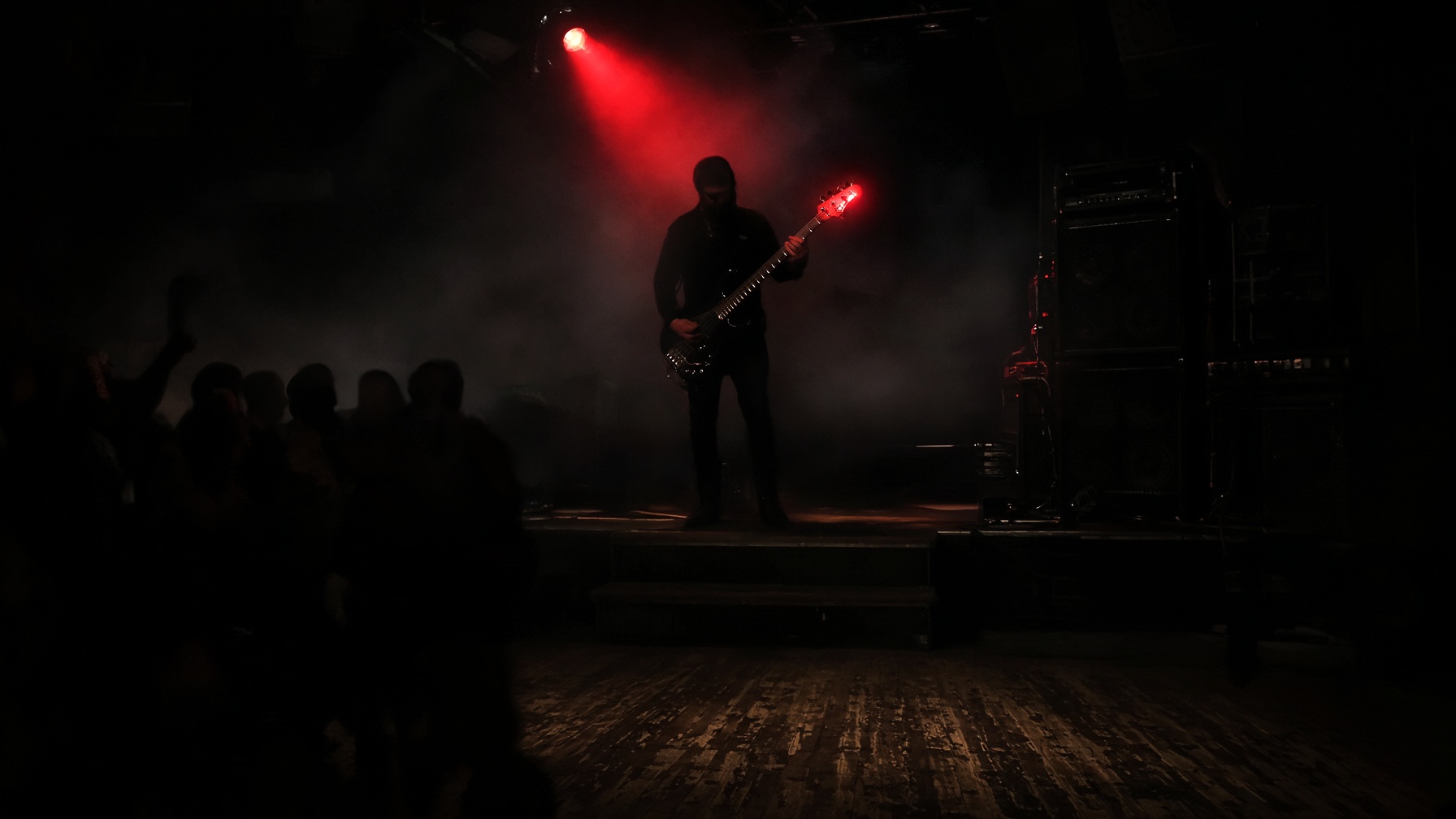 A guitarist in silhouette on a haze-filled metalcore stage